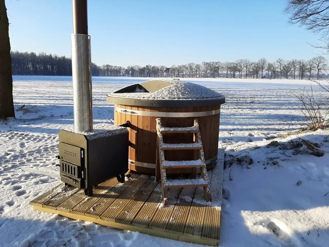 Welltub hottub in de winter met buiten kachel en sneeuw